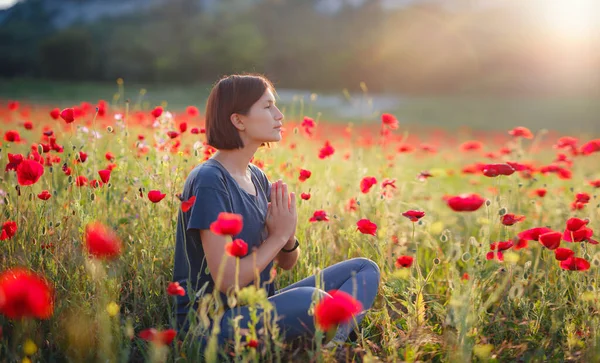 Una bella donna medita su un campo di papaveri al tramonto — Foto Stock