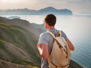 Genç adam dağların arka planında tek başına seyahat eder.