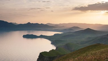 Deniz kıyıları ve dağların gün batımındaki büyüleyici manzara.