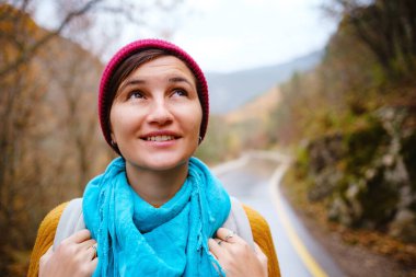 Sırt çantasıyla dağlarda yürüyen genç bir kadın.