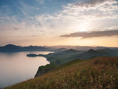 Deniz kıyıları ve dağların gün batımındaki büyüleyici manzara.