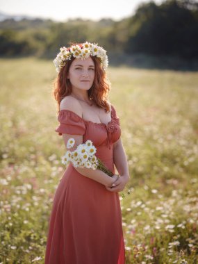 Bir yaz akşamı tarlada kızıl saçlı bir kadın.