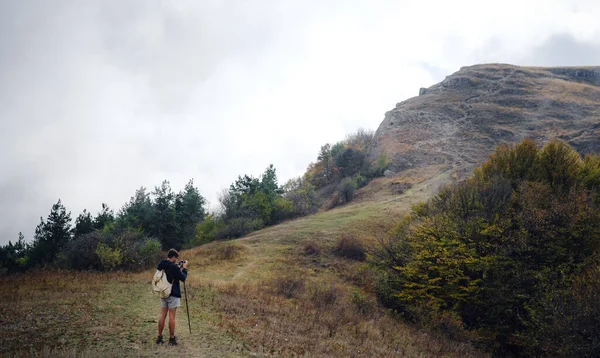 Man med ryggsäck och pinnar för vandring i bergen. — Stockfoto