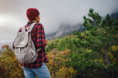 Sırt çantalı mutlu genç bir kadın sisli dağları keşfediyor. Seyahat ve seyahat tutkusu konsepti. İnanılmaz atmosferik an