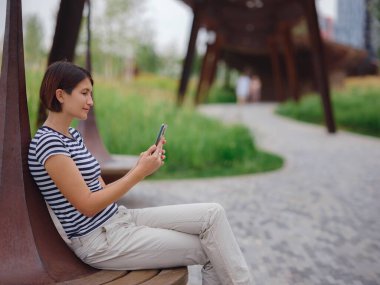 Güzel genç Asyalı kadın yaz günü çağdaş şehir parkında vakit geçiriyor..