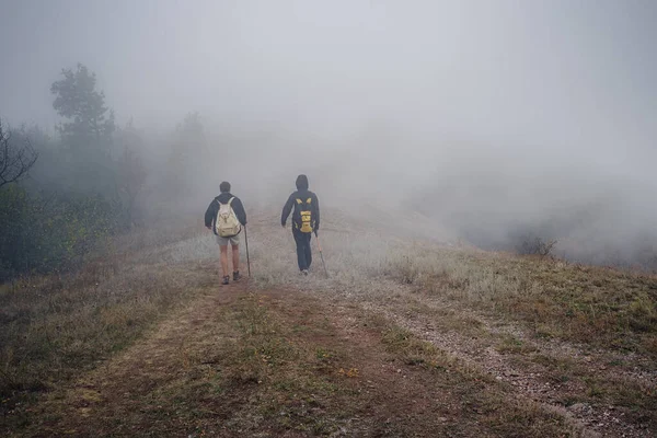 秋の霧の性質で一緒にバックパックハイキングと2人の男の友人 男性バックパッカーはリラックスして山道を歩くのをお楽しみください 健康的な屋外ライフスタイル休暇のコンセプト — ストック写真