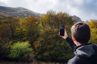 Kafkas sakallı bir adam akıllı telefon kullanarak vahşi doğada seyahat ediyor.
