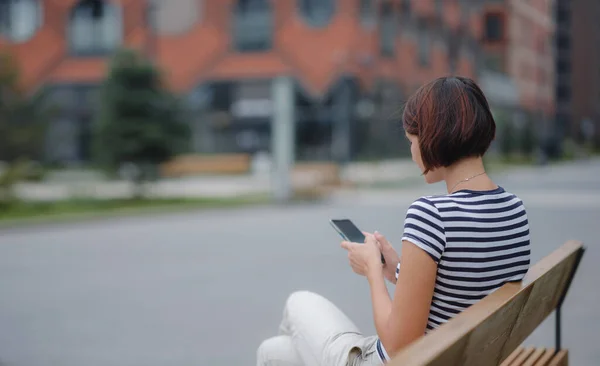 Mujer sonriente usando teléfono móvil en la calle —  Fotos de Stock