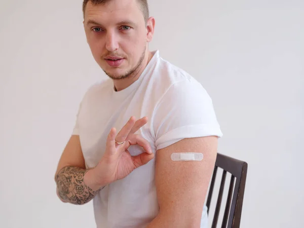 Homem caucasiano adulto sorridente mostrar ombro com ajuda banda após a injeção — Fotografia de Stock