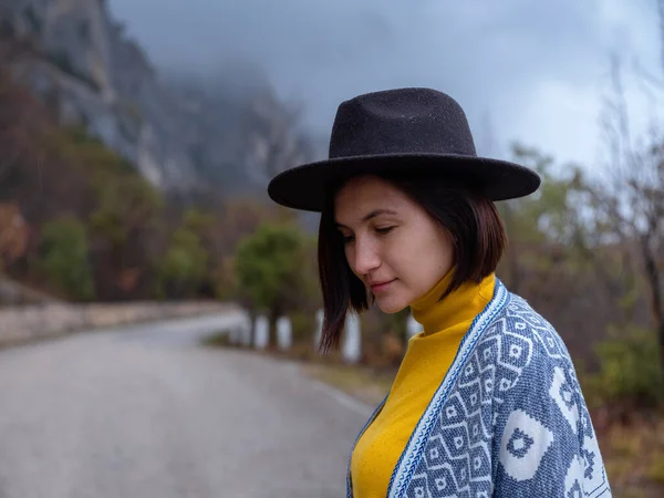Mulher hipster elegante em um chapéu andando por uma estrada de montanha — Fotografia de Stock
