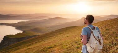 Genç adam dağların arka planında tek başına seyahat eder.