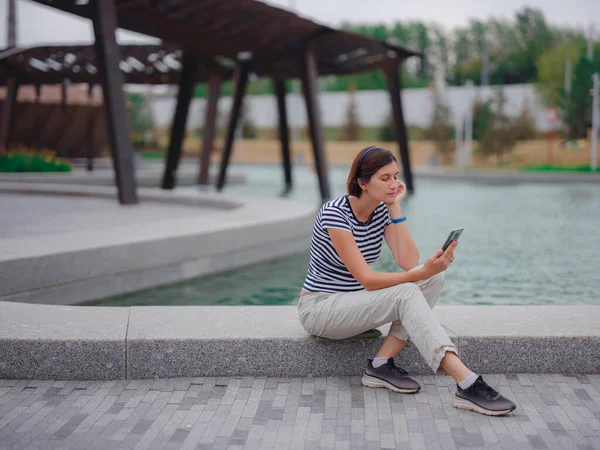 Parkta akıllı telefonlu genç bir kadının portresi