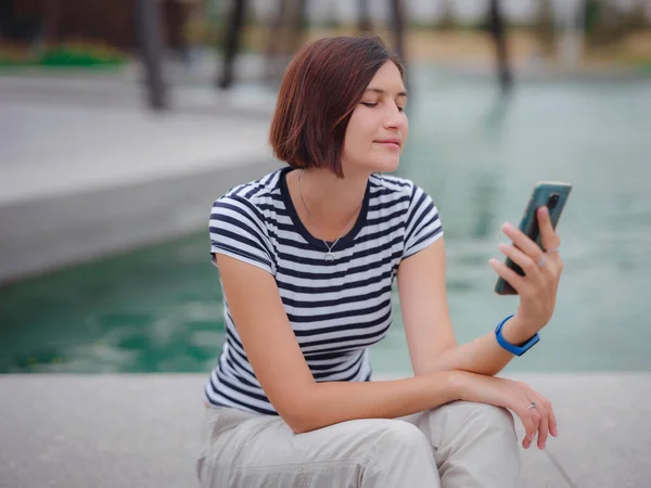 Retrato de mujer joven en el parque con smartphone —  Fotos de Stock