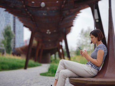 Güzel genç Asyalı kadın yaz günü çağdaş şehir parkında vakit geçiriyor..