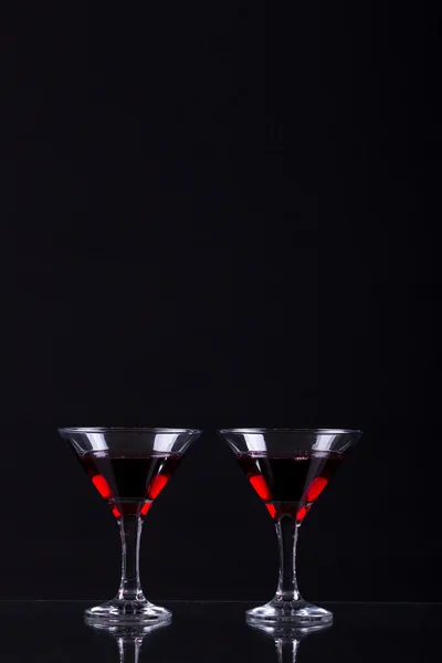 Vino rosso in due bicchieri di martini su fondo nero — Foto Stock