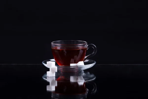 Taza de té negro con rodajas de azúcar sobre un fondo negro —  Fotos de Stock