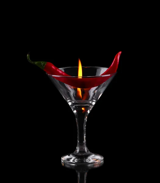Hot chili pepper in a martini glass with a fire on a black background — Stock Photo, Image