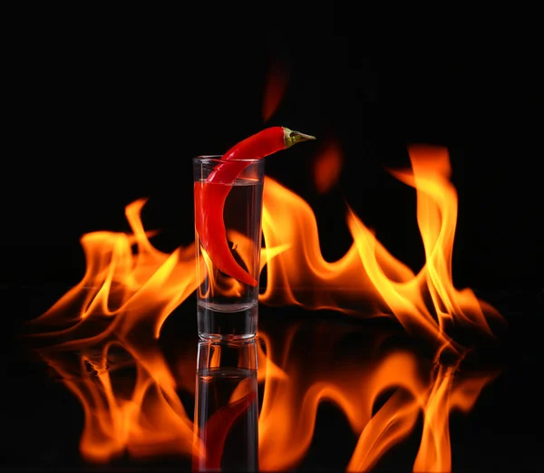 Chilischote in einem Schnapsglas mit Feuer auf schwarzem Hintergrund — Stockfoto