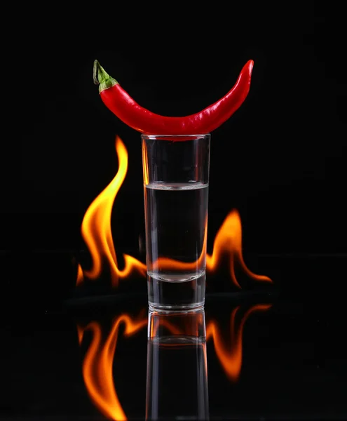 Hot chili pepper in a shot  glass with a fire on a black background — Stock Photo, Image