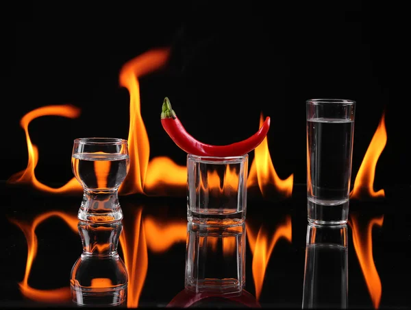 Hot chili pepper in a shot  glass with a fire on a black background — Stock Photo, Image