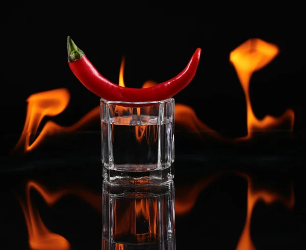 Pimienta picante en un vaso de chupito con fuego sobre fondo negro — Foto de Stock