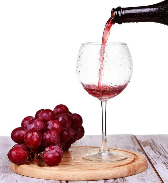 Wine pouring into glass with grape and bottles isolated — Stock Photo, Image