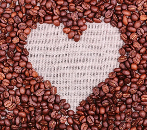 Marco de café corazón hecho de granos de café en textura de arpillera — Foto de Stock