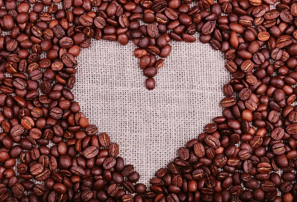 Marco de café corazón hecho de granos de café en textura de arpillera — Foto de Stock