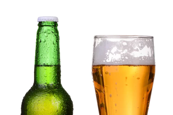 Охлажденная зеленая бутылка с конденсатом и стакан пива на белом фоне — стоковое фото