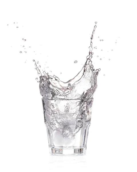 Ледяные кубики, брызгающиеся в стакан воды, изолированные на белом — стоковое фото