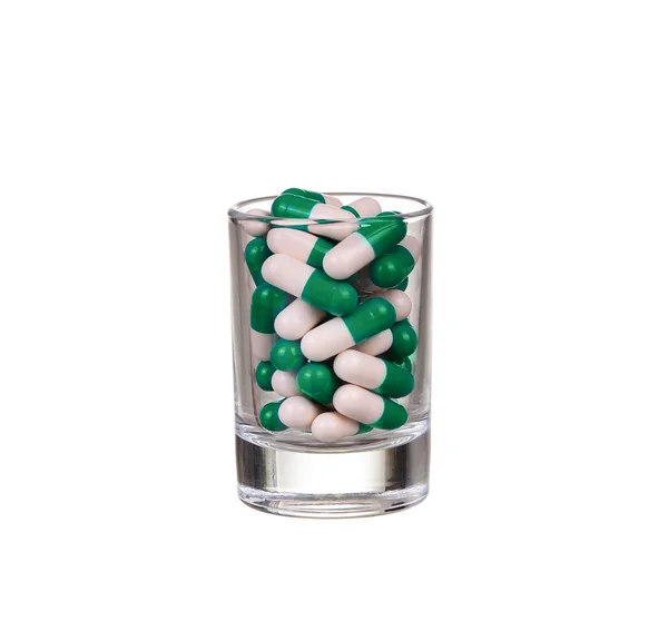 Kieliszek tabletki i kapsułki na białym tle — Zdjęcie stockowe