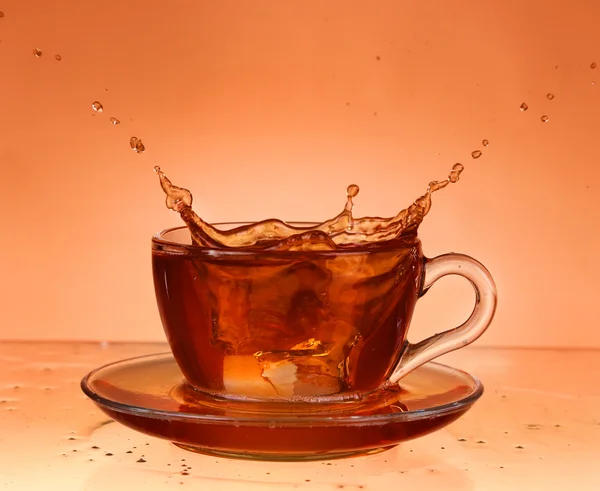 Taza de té sobre vidrio con fondo naranja — Foto de Stock