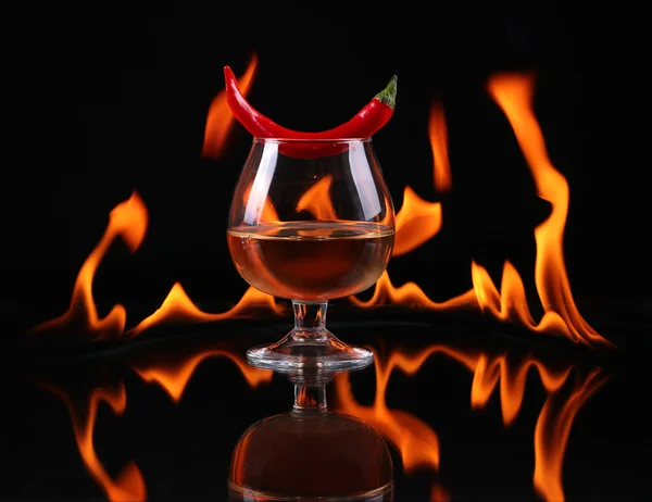 Hot chili pepper in a  cognac ballon with a fire on a black background — Stock Photo, Image