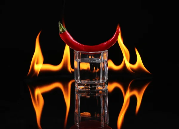 Papryczka chili w kieliszku z ogniem na czarnym tle — Zdjęcie stockowe