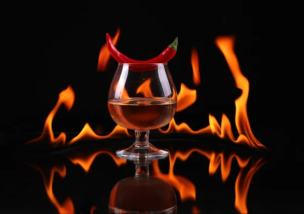 Hot chili pepper in a  cognac ballon with a fire on a black background — Stock Photo, Image