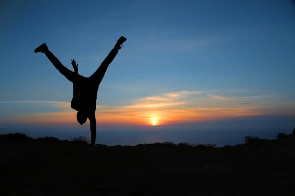 Silhouette des Menschen am Sonnenuntergang auf dem Felsen — Stockfoto