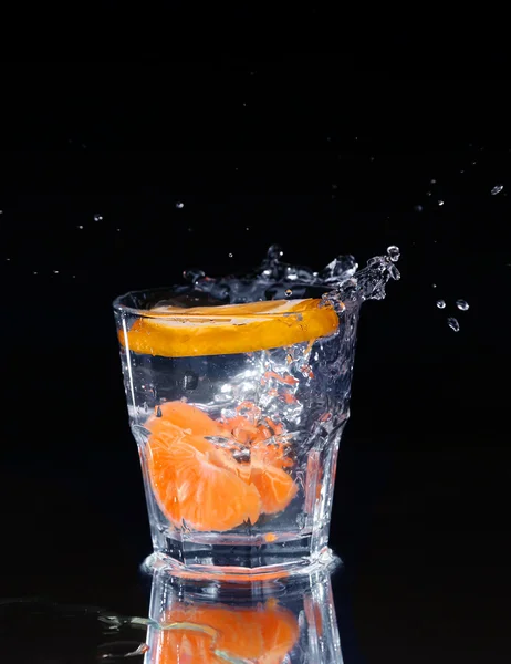 Fetta di limone spruzzata in un bicchiere d'acqua con uno spruzzo di acqua — Foto Stock