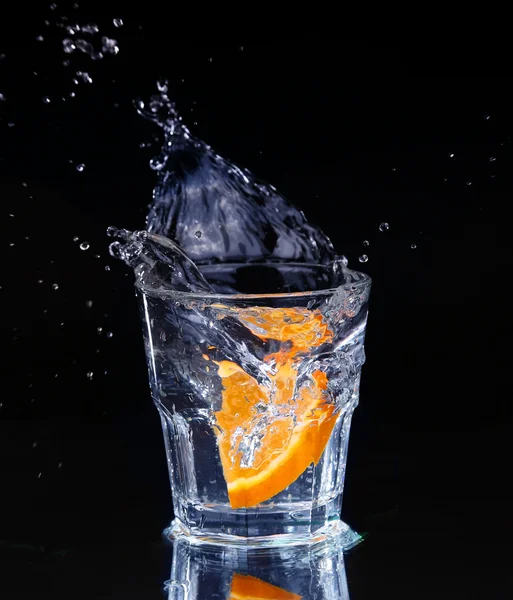 Fetta di limone spruzzata in un bicchiere d'acqua con uno spruzzo di acqua — Foto Stock