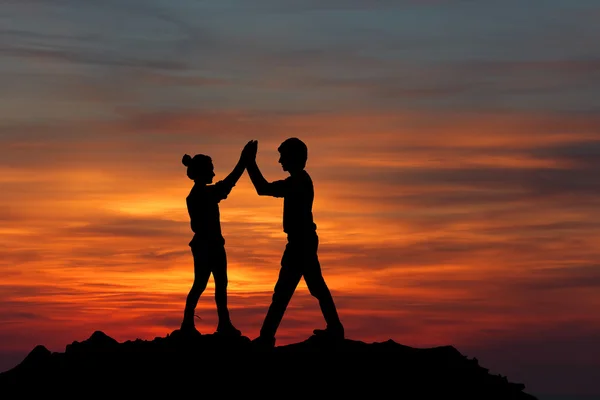 The Silhouette of two man with success gesture standing on the top of mountain — Stock Photo, Image