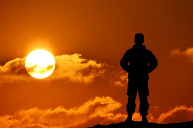 Bir gün batımı karşı tüfekle asker silüeti