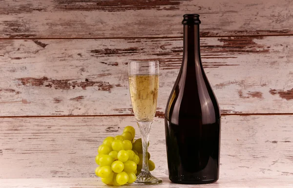 Glas wijn, een fles wijn en druiven aan boord — Stockfoto