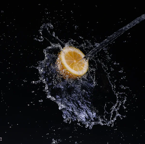 Высокоскоростной снимок лимона с брызгами воды на черном фоне . — стоковое фото