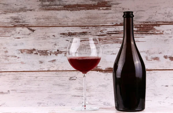 Botella de vino tinto sobre un fondo de madera — Foto de Stock