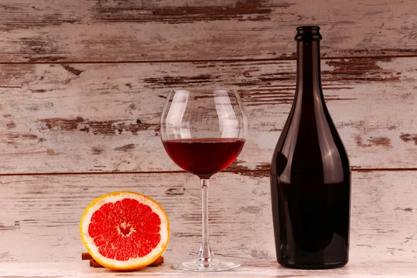 Copa de vino tinto, una botella de vino y pomelo en la tableta — Foto de Stock