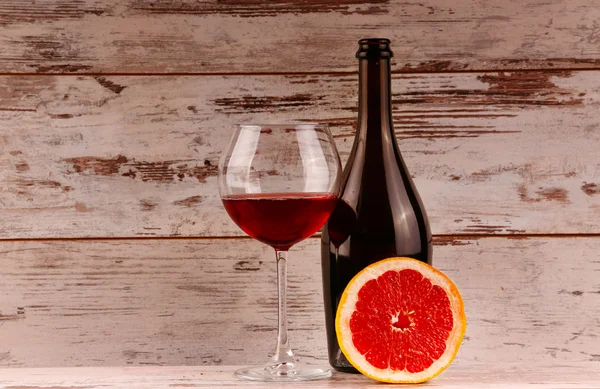 Glas rött vin, en flaska vin och grapefrukt på tabletten — Stockfoto