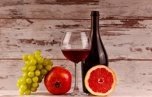 Botella de vino tinto sobre fondo de madera, manzana y granada — Foto de Stock