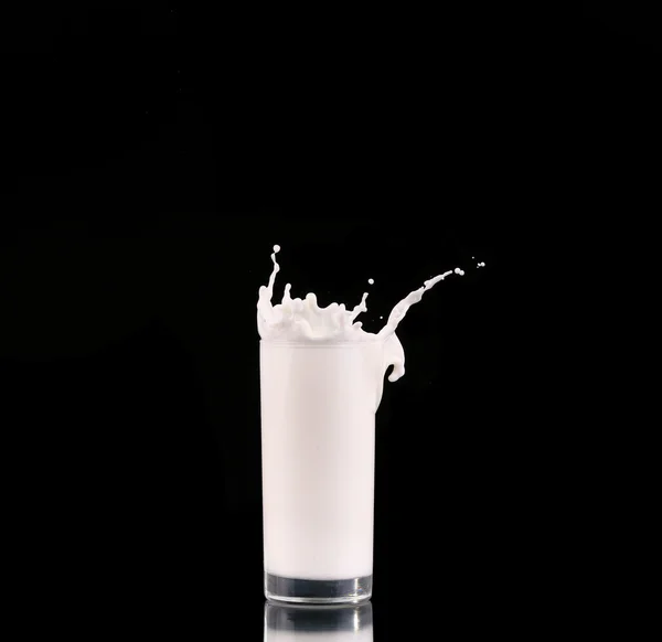 Spritzer in einem Glas mit Milch isoliert auf schwarz — Stockfoto