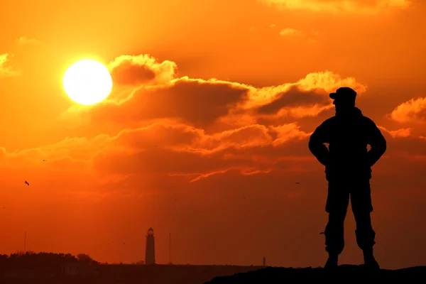 Silhouette shot of soldier holding gun with colorful sky and mountain in background — Stock Photo, Image