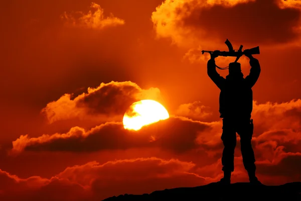 Silhouettenaufnahme eines Soldaten mit Gewehr mit buntem Himmel und Berg im Hintergrund — Stockfoto