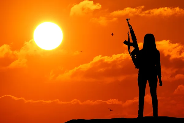 Una silueta de una mujer apuntando su arma en el cielo . — Foto de Stock